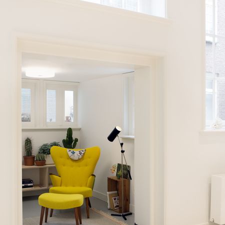 Gelber Sessel in einem modernen Raum mit Pflanzen, einem Holzregal und einer Stehlampe