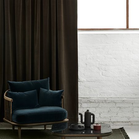 Gemütliche Wohnzimmerecke mit einem dunkelgrünen Samtsofa, einem stilvollen Couchtisch und einem Teeservice