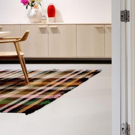 Raum mit einem gemusterten Teppich auf dem Boden, einem Holzstuhl und minimalistischen Schränken