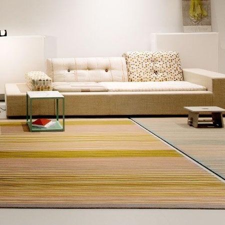 Modernes Wohnzimmer mit einem beigen Sofa, Beistelltischen und gestreiften Teppichen in warmen Tönen