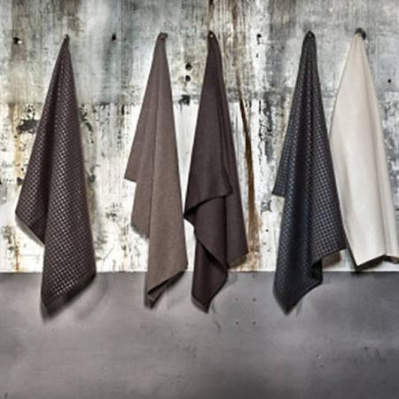 Sechs Stoffe in verschiedenen Braun- und Cremetönen hängen vor einer strukturierten grauen Wand