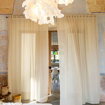 Einrichtung mit durchsichtigen Vorhängen, einer strukturierten Decke und kunstvollen Lampen