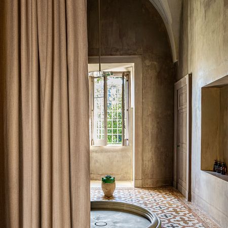 Raum mit gewölbten Decken, einer Natursteindusche, einem großen Fenster und einem gemusterten Fliesenboden