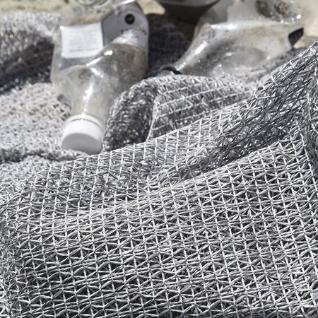 Eine Nahaufnahme eines strukturierten grauen Stoffes mit mehreren Flaschen, die teilweise im Sand vergraben sind