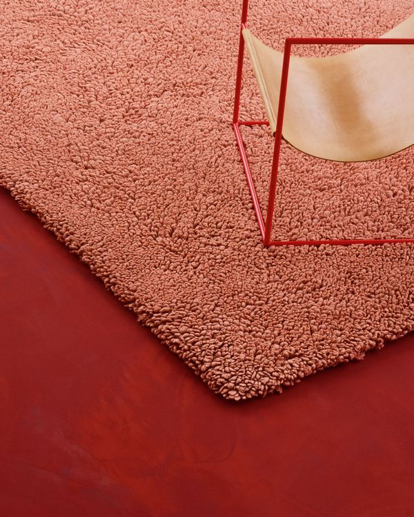 Auf einem roten Boden befindet sich ein Stuhl und ein dekorativer roter Teppich.