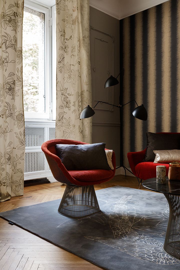 Stilvolle Einrichtung mit roten Stühlen, einem grauen Teppich mit Blumenmuster und eleganten Vorhängen