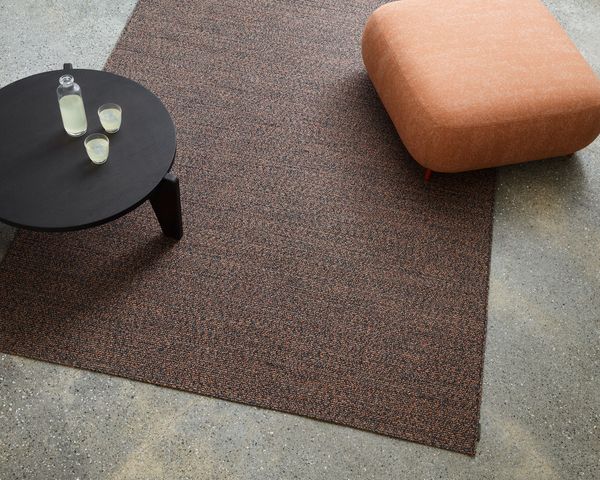 Ein dekorativer Teppich auf dem Boden mit einem kleinen Tisch und einem Glas Wasser darauf.